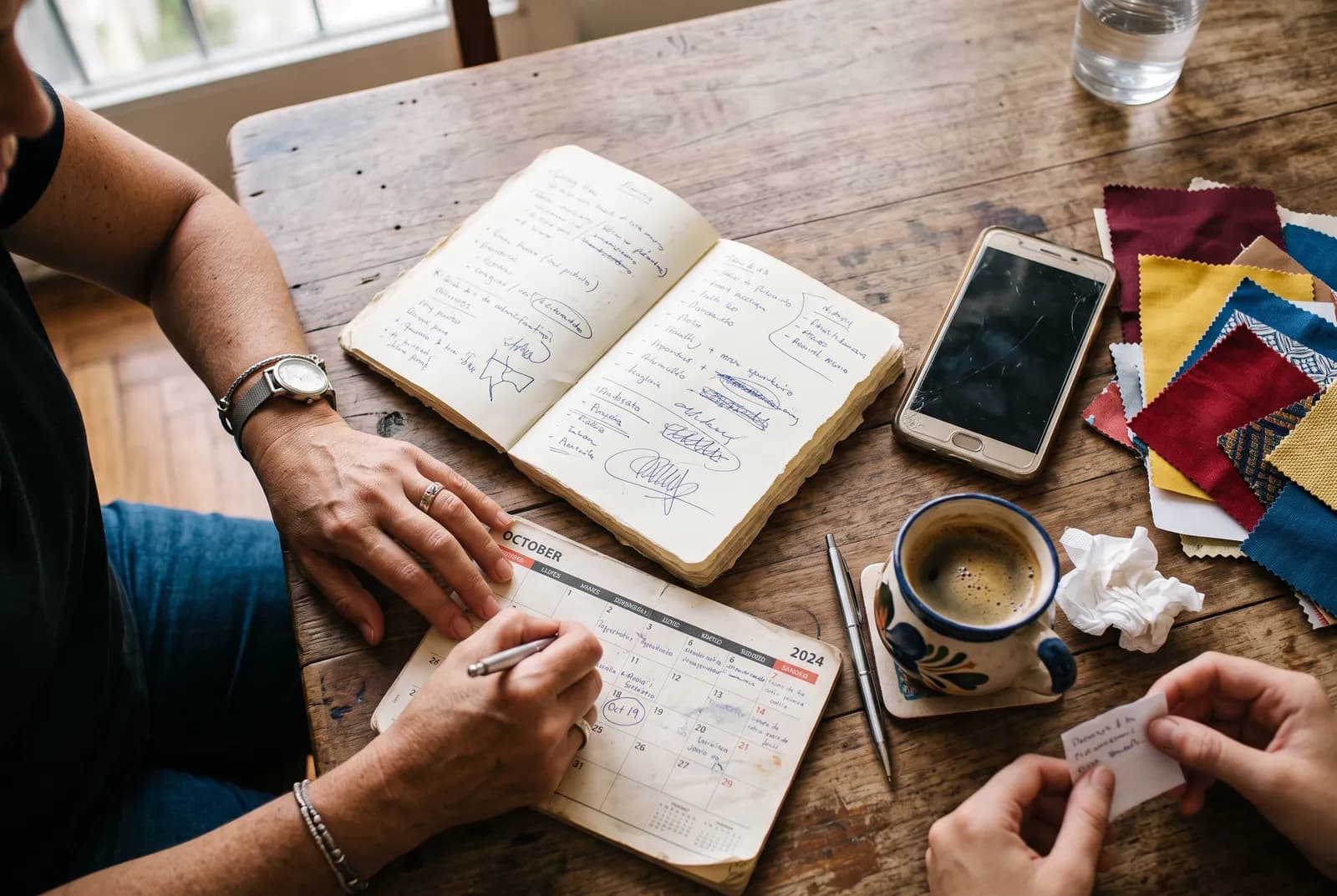 Cuaderno abierto con una lista de tareas, una birome y un café sobre una mesa